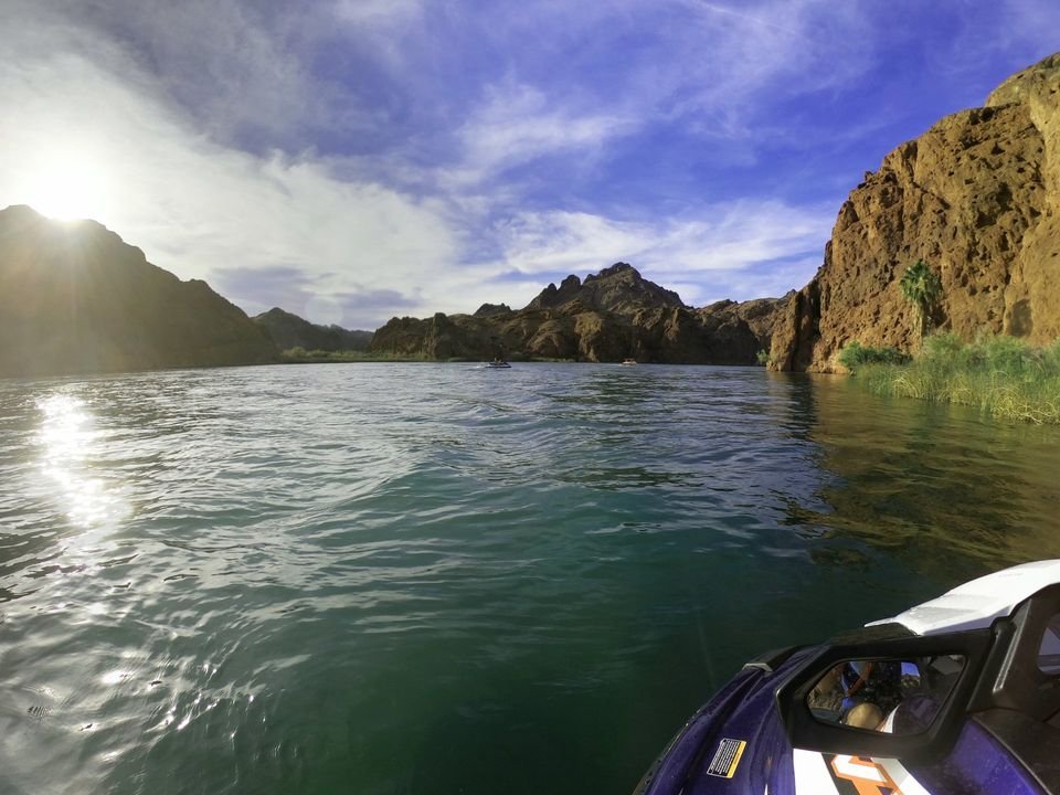 View from the seat of a jet ski on a sunny day, traveling through a river canyon with rocky cliffs and blue water.