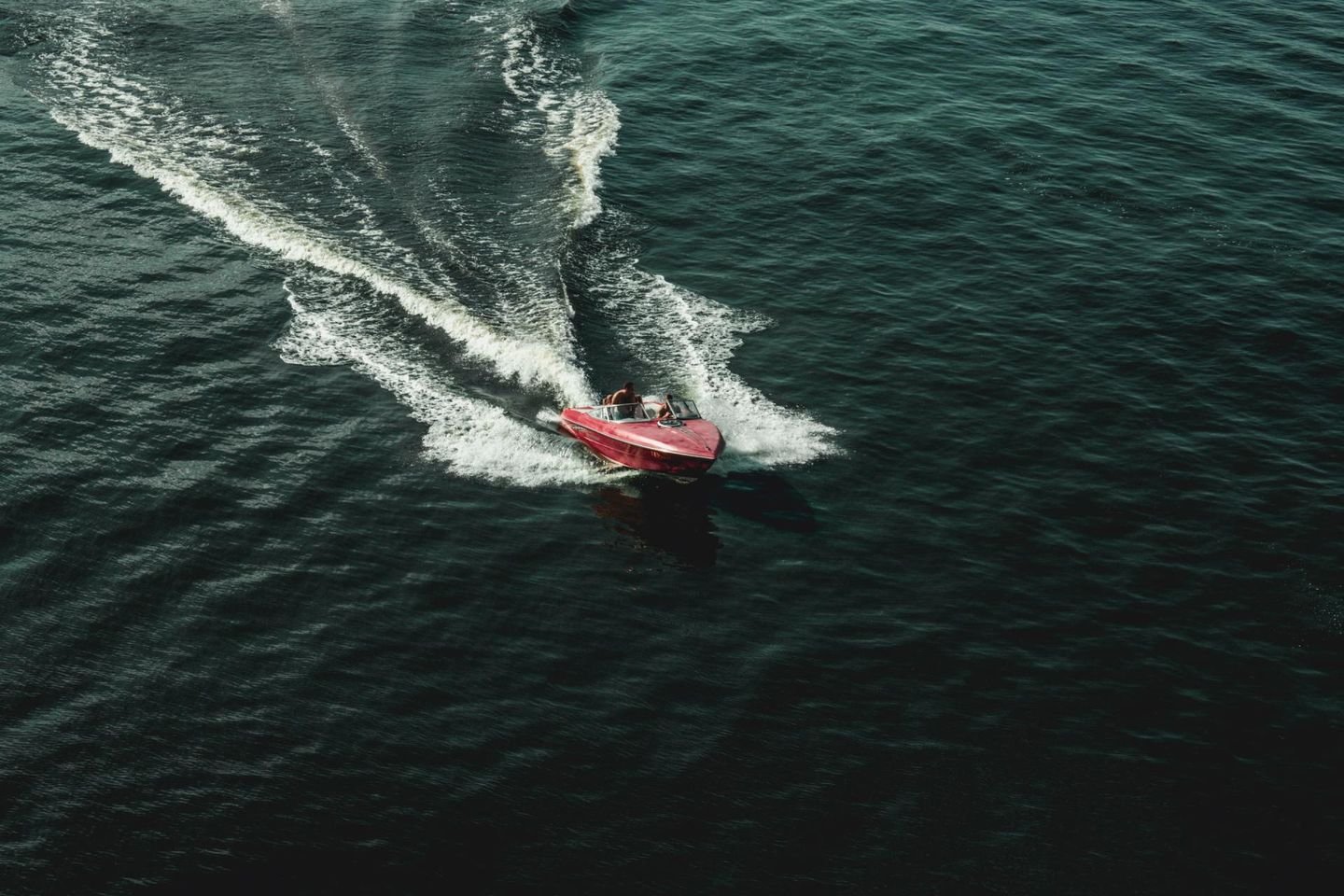 Aerial view of a small boat leaving a wake on dark water